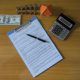 Contrato de vivienda sobre una mesa junto a calculadora y otros elementos