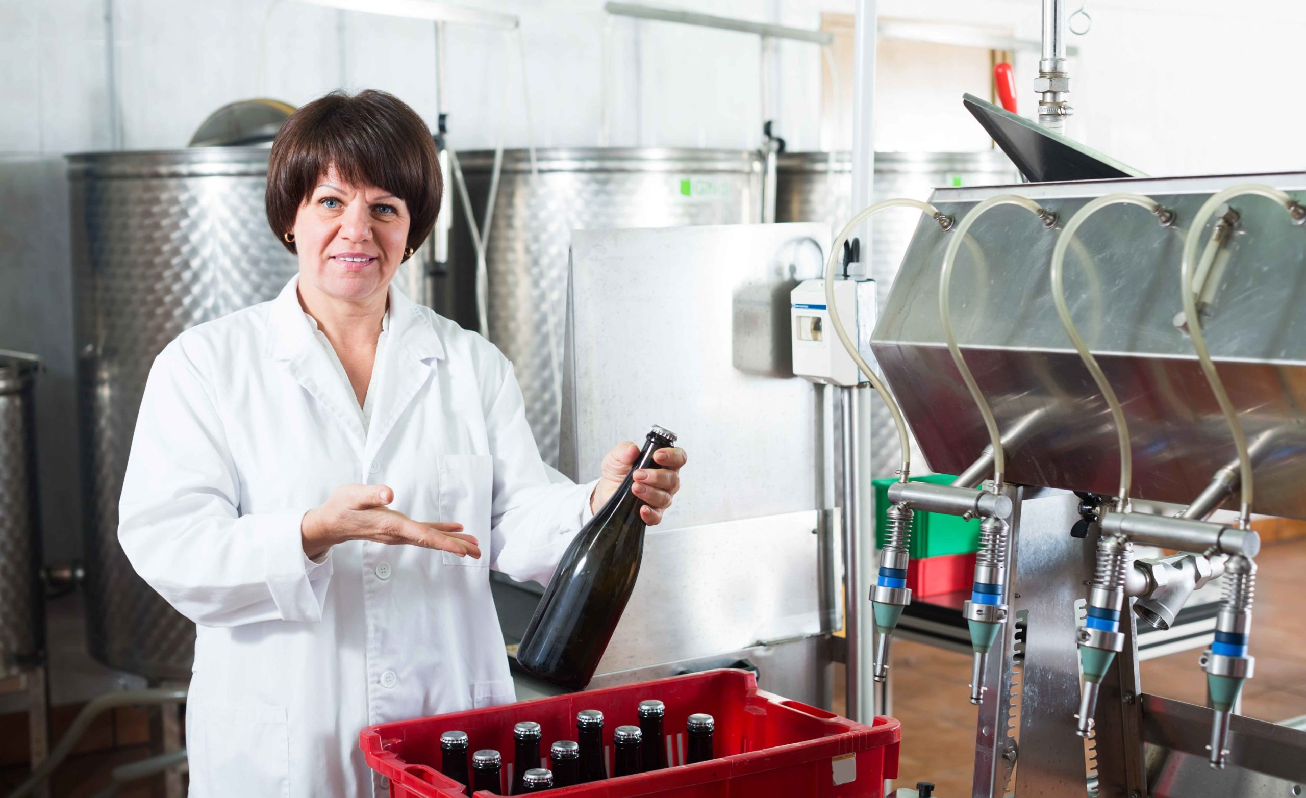 Mujer posando con bebidas en una fábrica