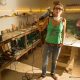 Chica en taller de carpintería posando con herramientas de trabajo