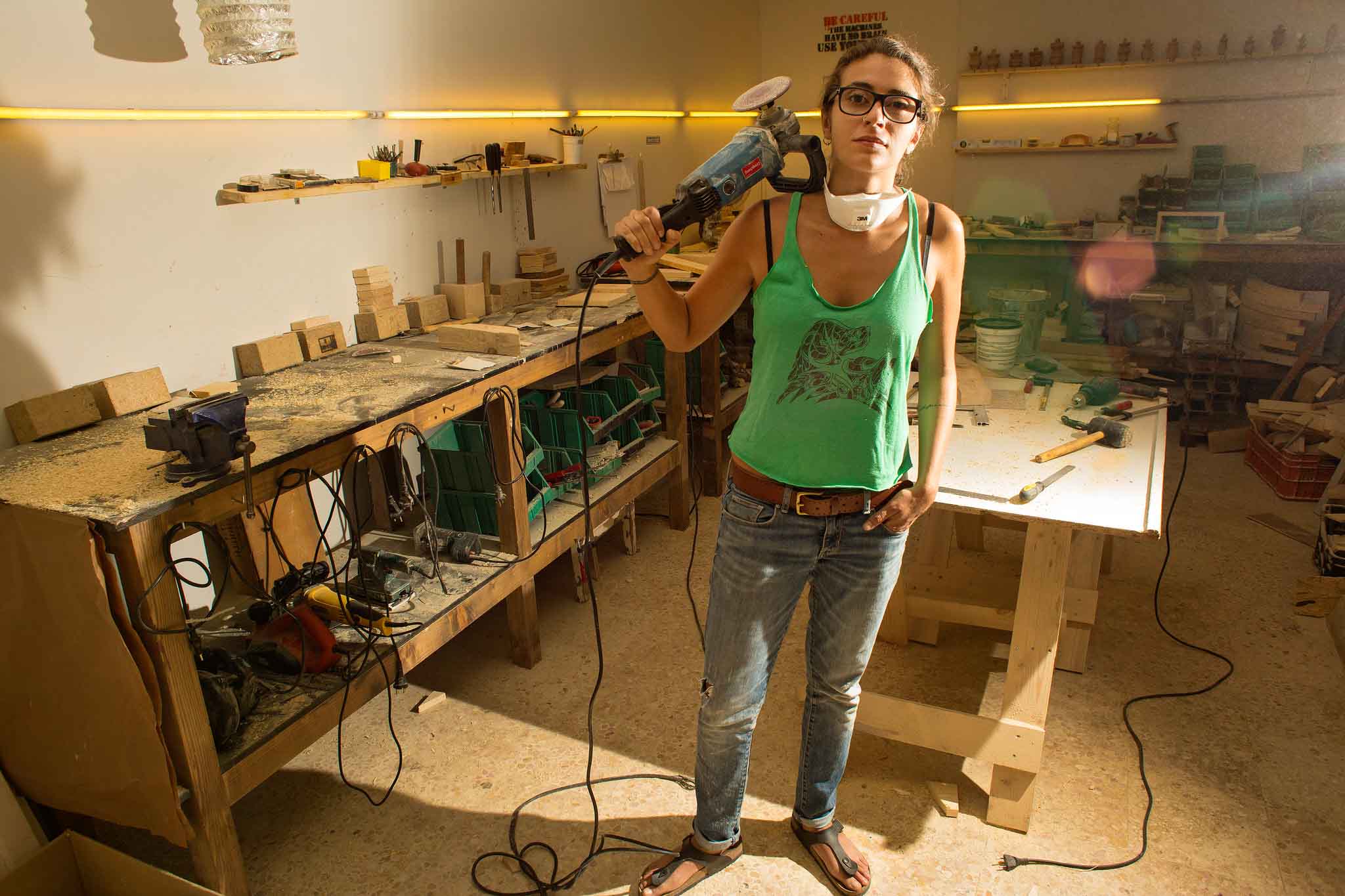 Chica en taller de carpintería posando con herramientas de trabajo