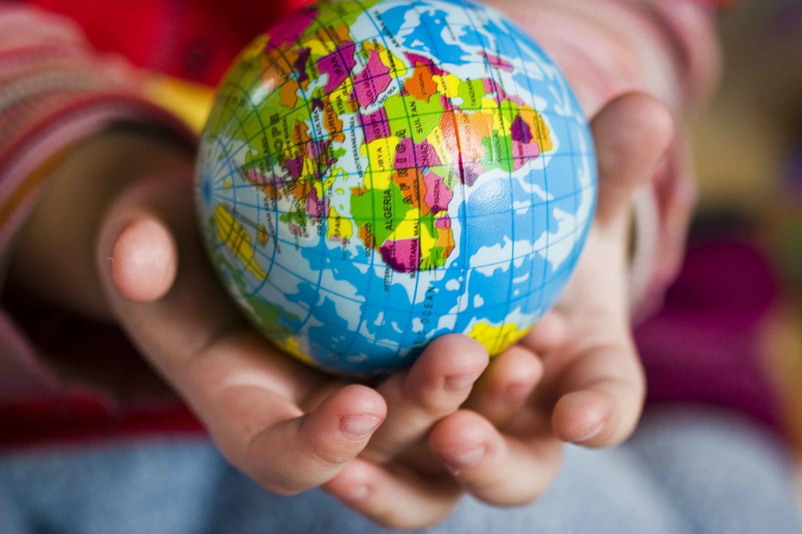 Manos de niño con bola del mundo en la mano