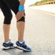 Runner parada en medio de la carretera tocándose la rodilla con dolor