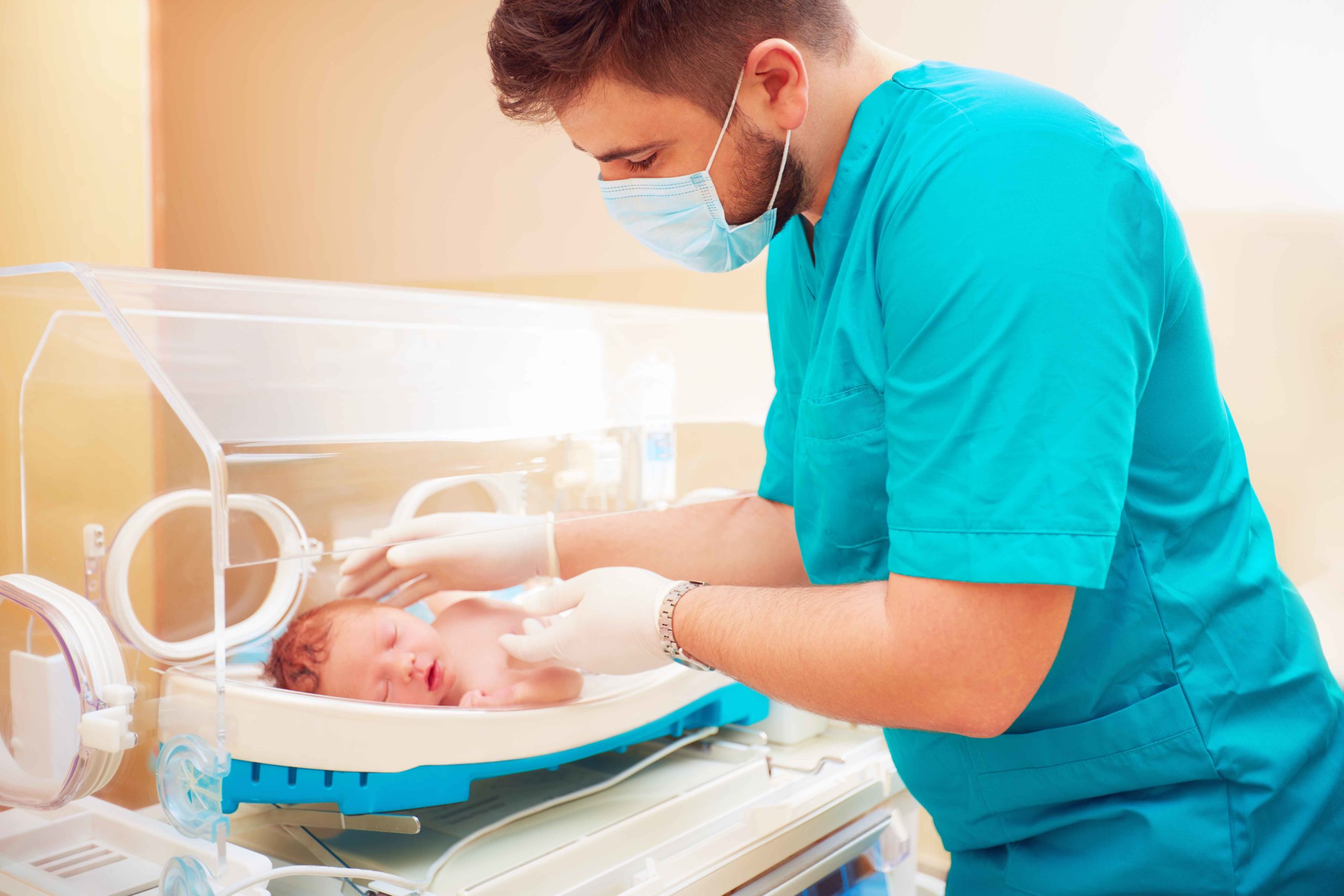Doctor atiendiendo a bebé en incubadora