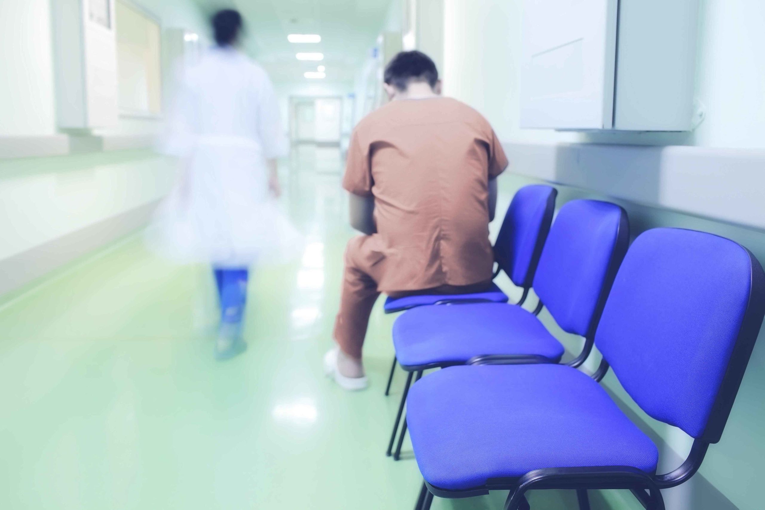 Hombre de espaldas en sala de espera y doctor yéndose al fondo