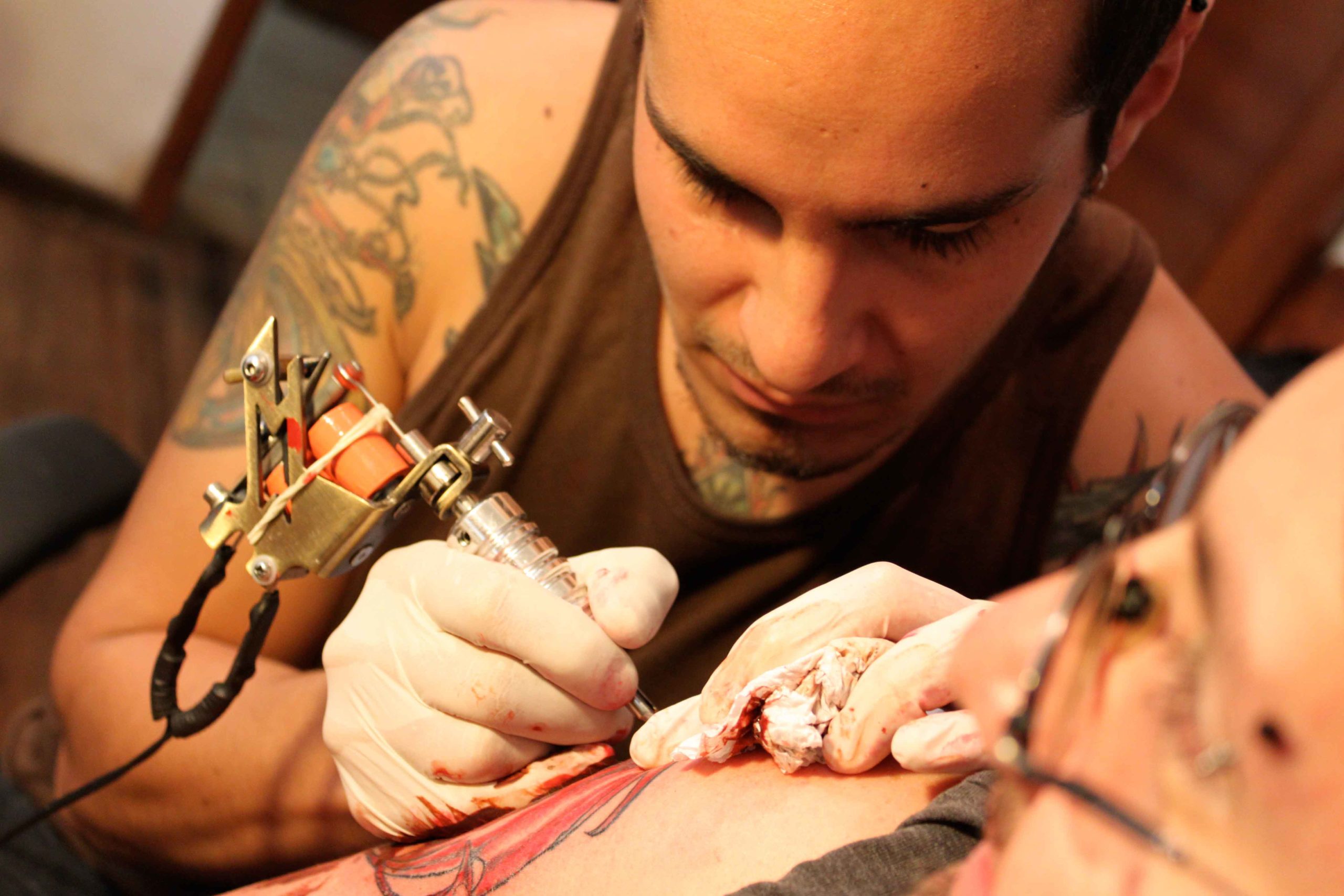 tatuador realizando una obra en un brazo